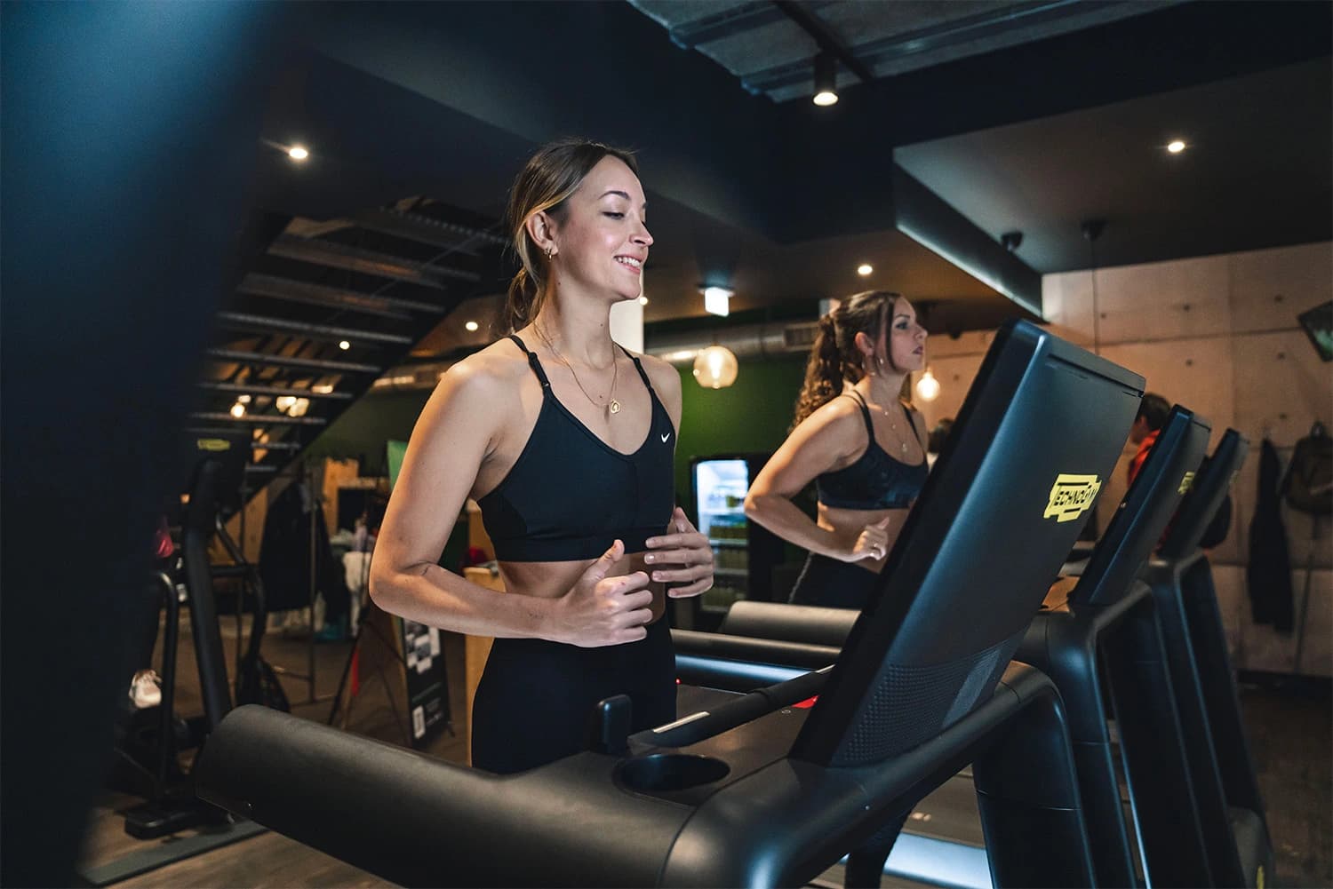 Femme souriant sur tapis de course en salle de sport Keepcool, entraînement cardio en club fitness.