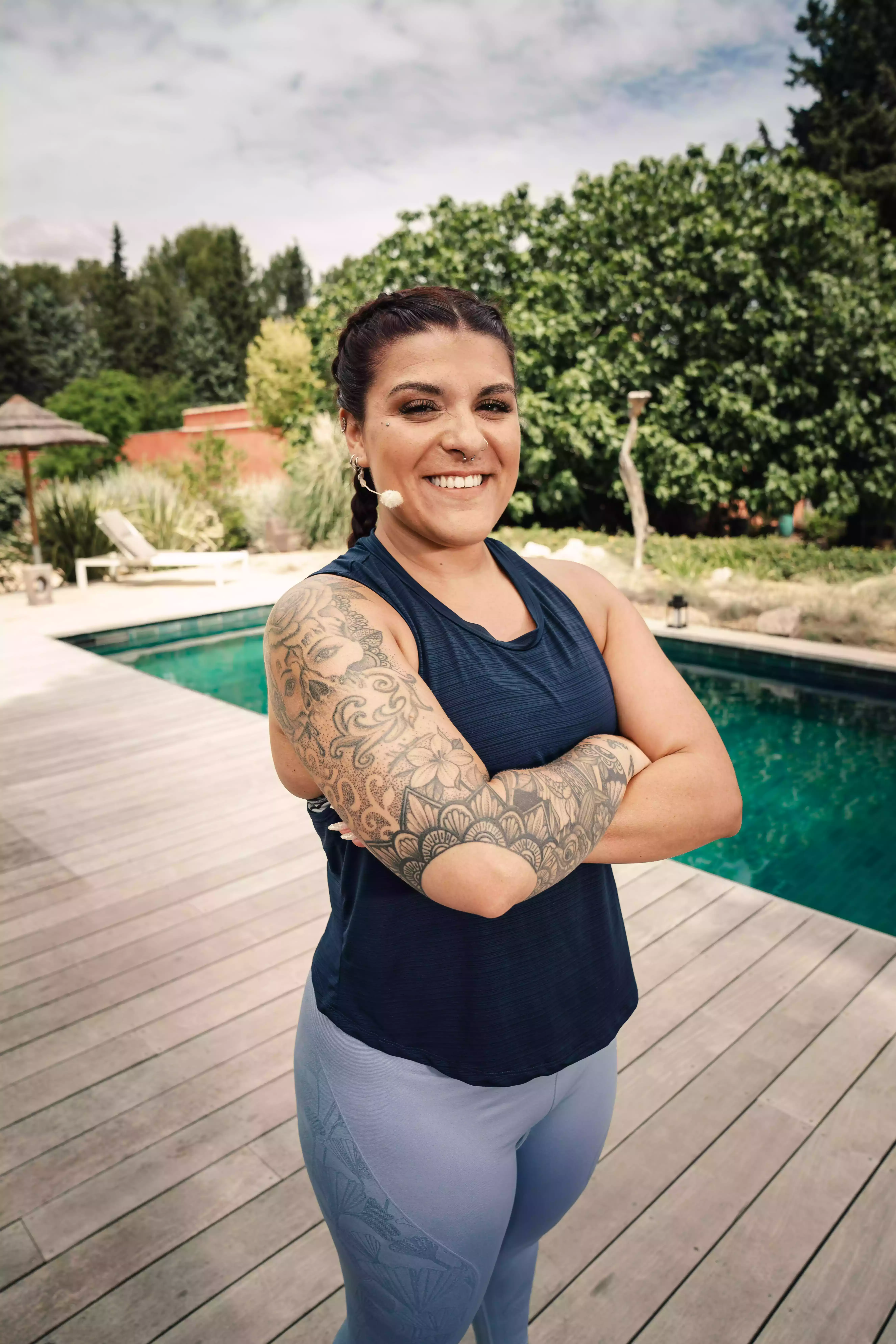 Femme souriante tatouée portant tenue sportive près piscine, salle fitness Keepcool.