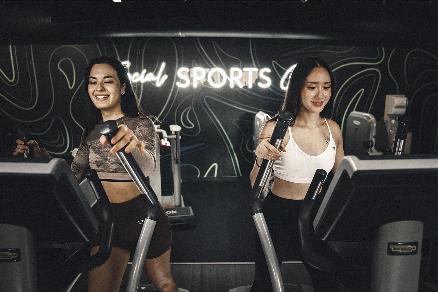 Deux femmes utilisant des appareils elliptiques en salle de sport Keepcool pour séance cardio.